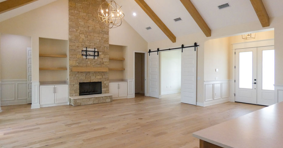 Spacious living room with fireplace, white walls, and wooden beams