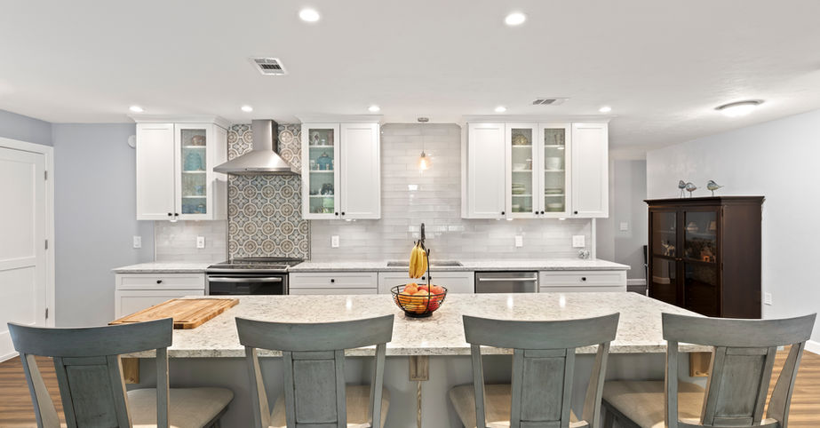 Modern kitchen with white cabinets, island seating, and stainless steel appliances.