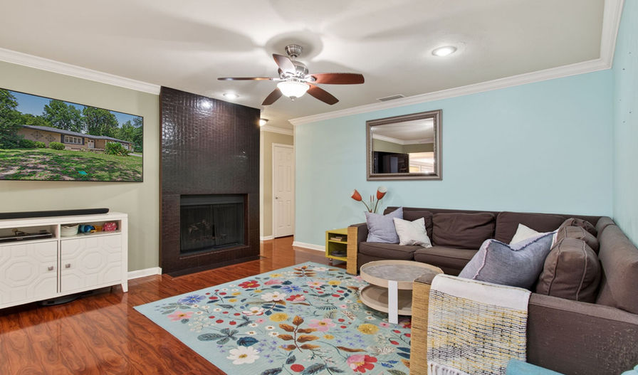 Living room with brown sofa, fireplace, and colorful rug