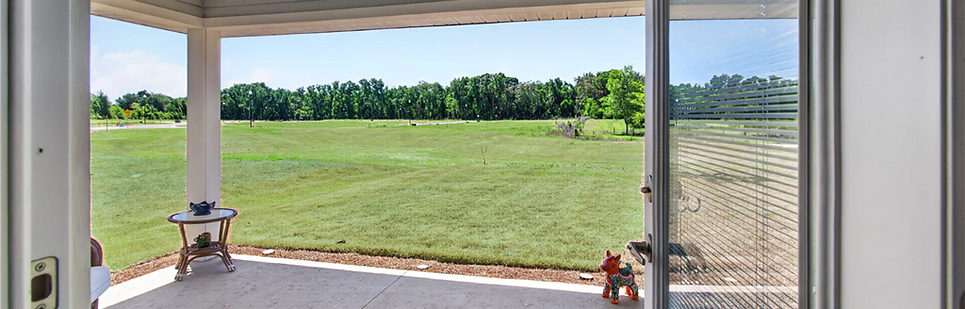 View from covered patio to green field and trees