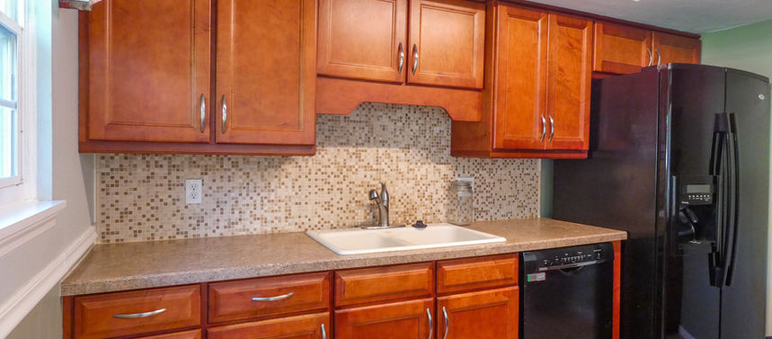 Kitchen with wooden cabinets, sink, dishwasher, and refrigerator; Northwood Pines $230,000