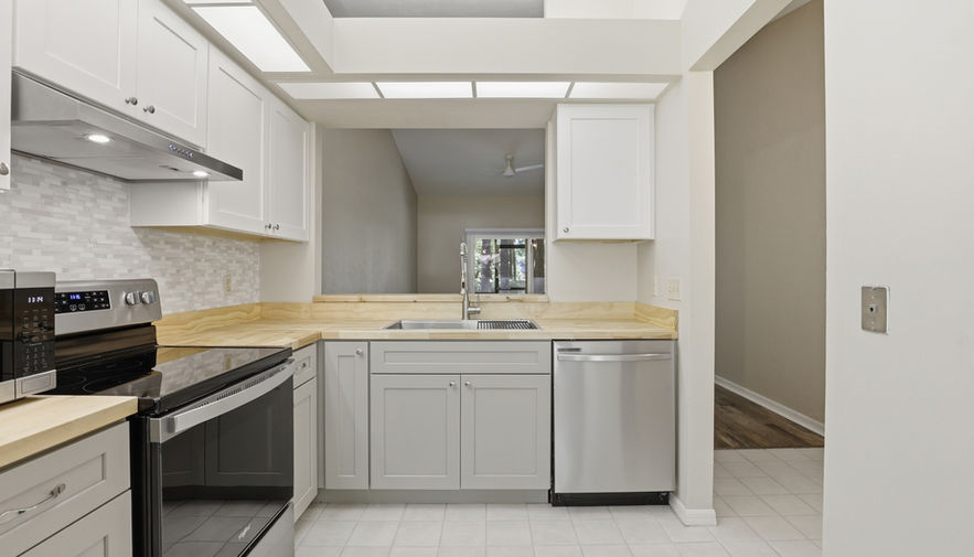 Kitchen with light grey cabinets, stainless appliances, tile floor