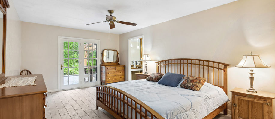 Bedroom with bed, dresser, lamps, and outdoor view, spacious and bright.