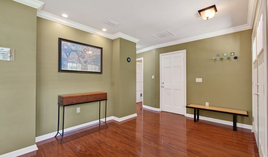 Home entryway with olive green walls, dark wood floor, and bench