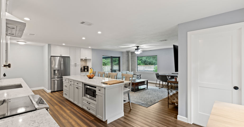 Modern kitchen with island and connected living room, Kenwood $502,600, hardwood floors.