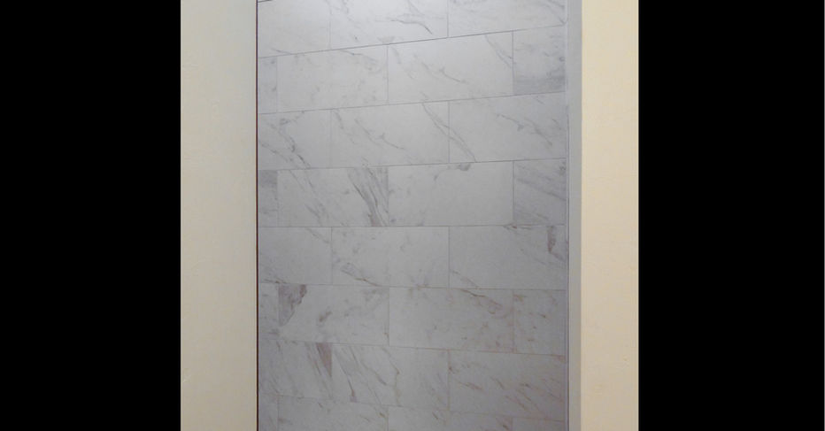 White tiled shower interior with glass door and light colored walls