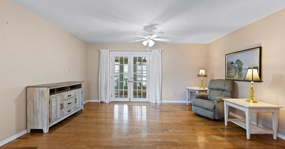 Spacious living room featuring hardwood floors, French doors, and comfortable seating arrangement.