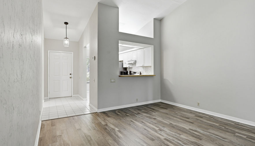 Empty living room with wood floor and kitchen pass-through