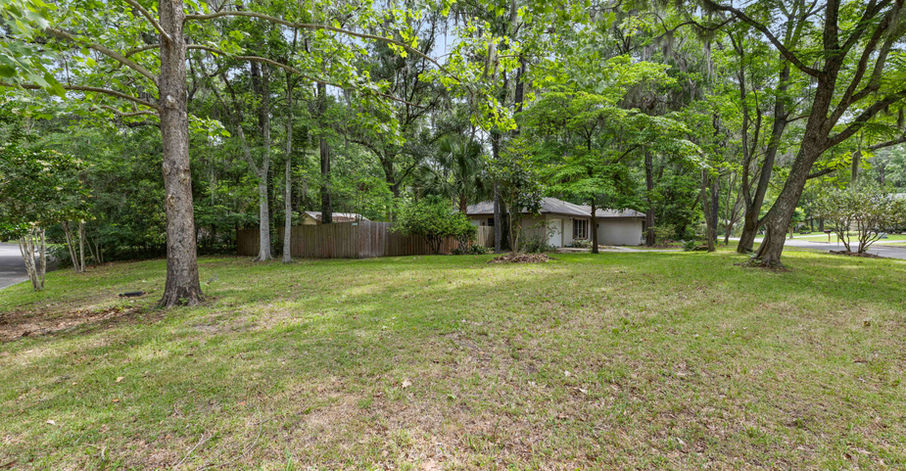 Green lawn with trees and a house in the background scenery.