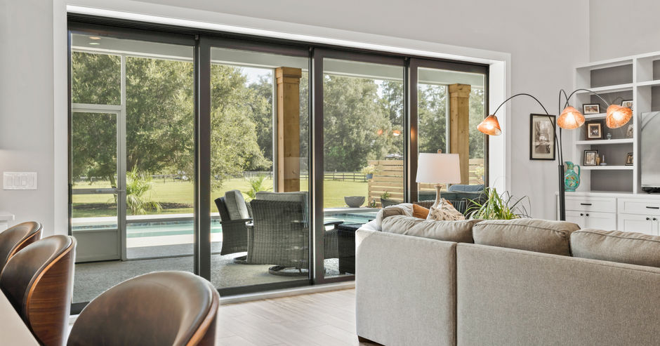 Living room with large sliding glass doors overlooking a pool and yard.
