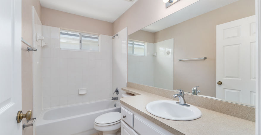 Clean bathroom with white cabinets, toilet, sink, and large mirror Sorrento $299,900