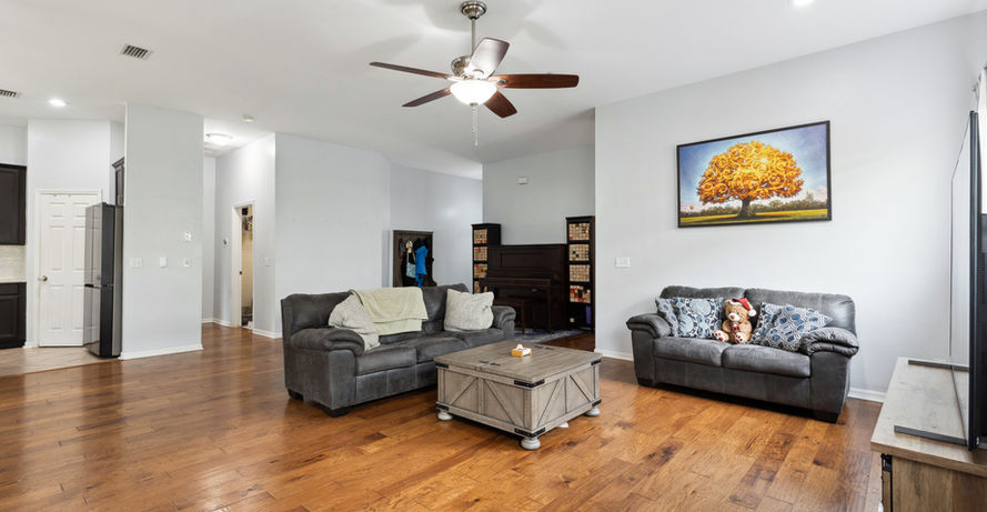 Spacious living room with two sofas, wooden floor, and decorative painting.
