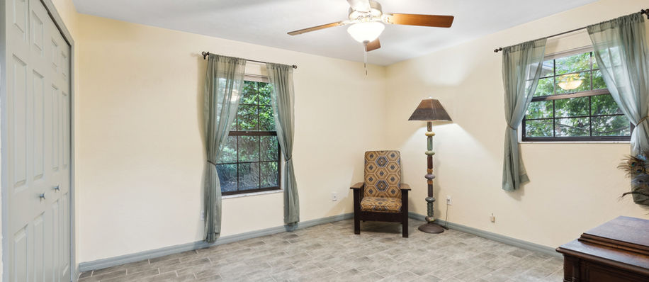 Bedroom with chair and windows; neutral walls and floor; natural light Blues Creek $405,000.
