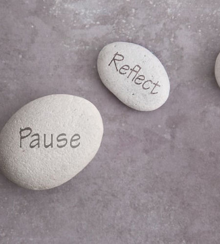 Stenar med orden ´pause´och ´reflect´som symboliserar mindfulness, återhämtning och att stanna upp i vardagen