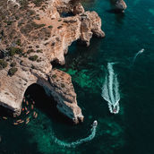 Drone shot of boats in the ocean along the coast of Lagos, Portugal, capturing the stunning seascape and coastal beauty.