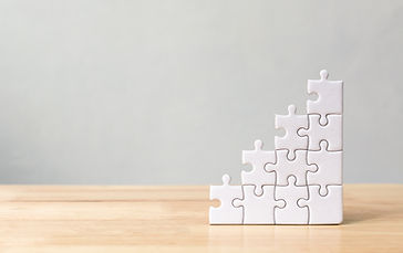 Jigsaw puzzle stacking as step stair on wooden table. Business concept for growth success 
