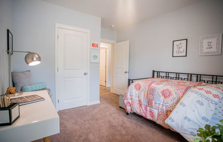 Interior of a bedroom looking toward the white entry door.