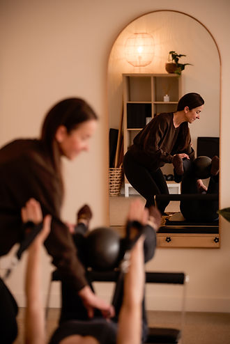 Pilates instructor providing personalised guidance during a small group Reformer class