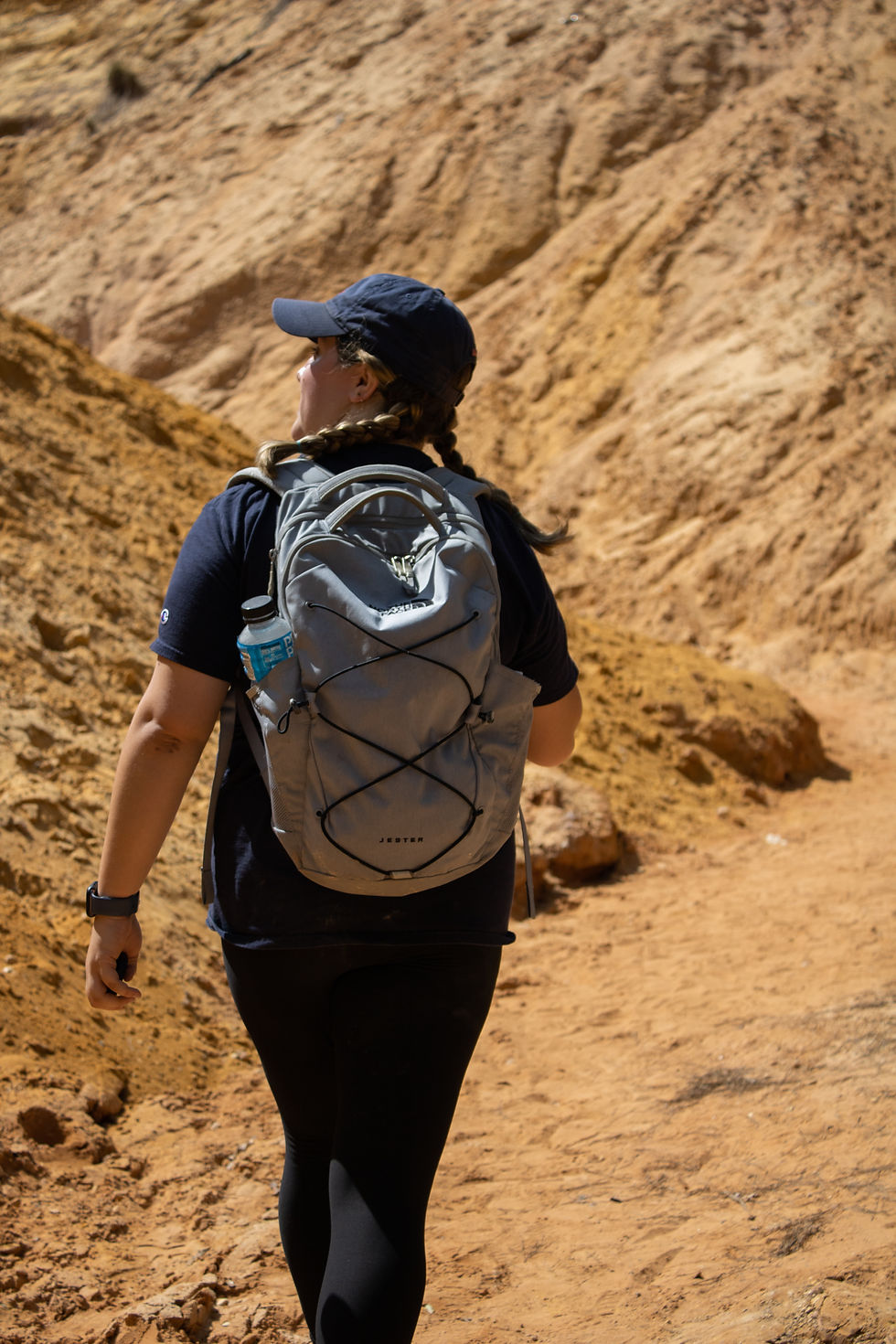 Girl walking away from camera with red dirt hills in front of her