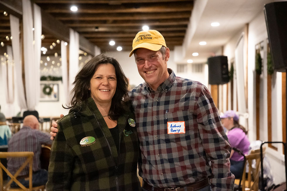 Nicole Masters and Anthony Beery in a yellow hat standing indoors.