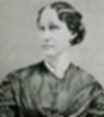 black and white photo of a woman in nineteenth-century dress. She wears a brooch at her neck and her hair is tied up.