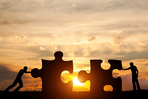 Two men connect two puzzle pieces. Sunset sky. Concept of business solution, teamwork, solving a pro