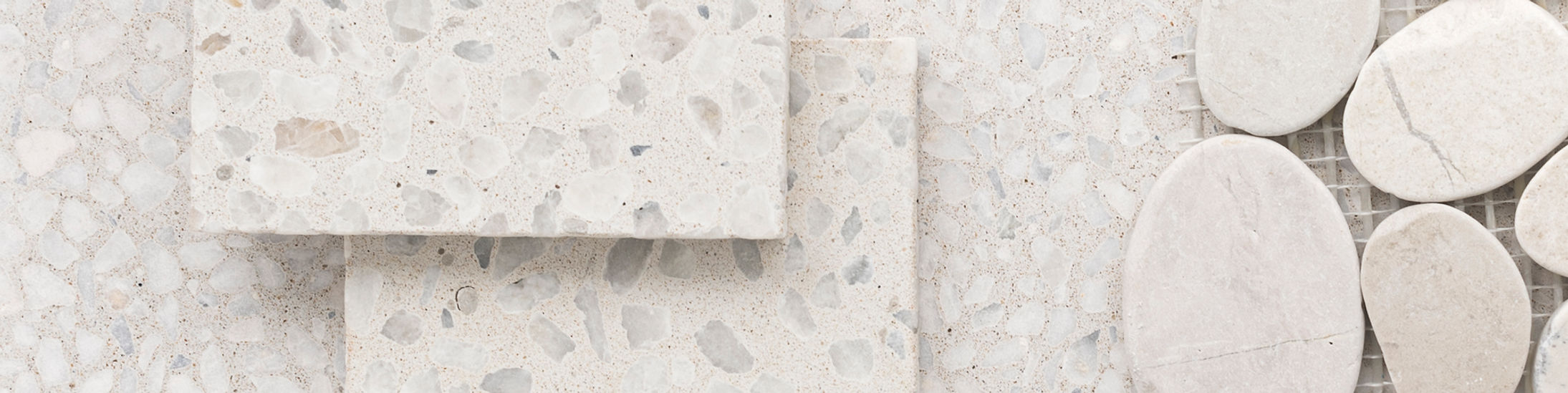Three white-ice terrazzo placed on top of each other, surrounded by white rock.