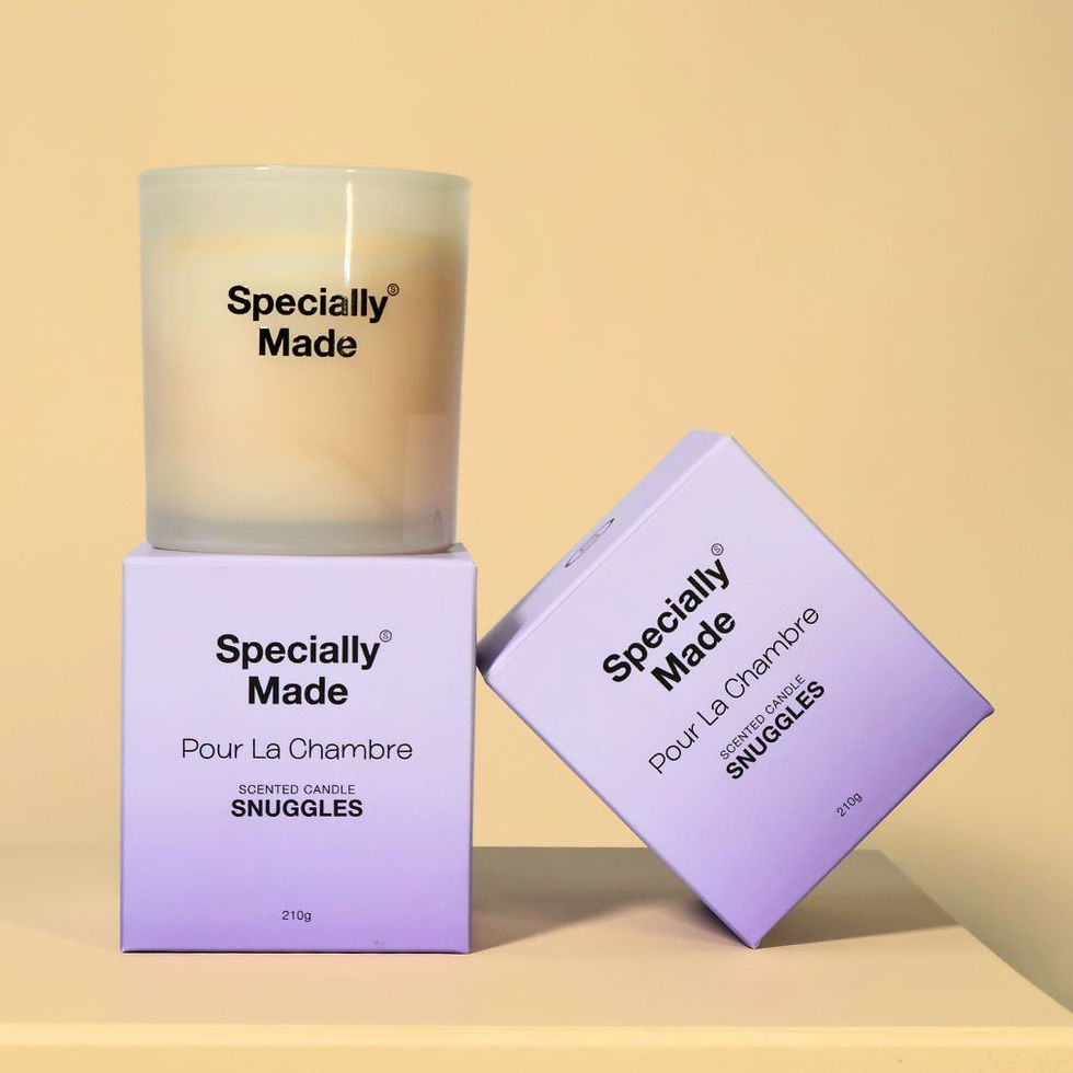 Snuggles Candle in a glass jar on top of its violet box. Both are set against an orange background.