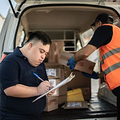 Person with an intellectual disability standing at the pack of a delivery van with a clipboard, overseeing the delivery