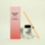 Adorabubble Reed Diffuser in its squat glass bottle next to its tall pink box. Reeds lean against the jar. Mint background