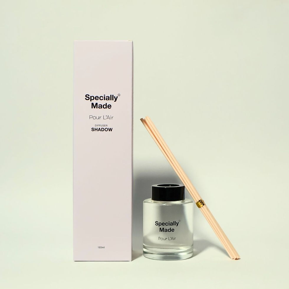 Shadow Reed Diffuser in a glass jar with reeds leaning on it. Beside it is its white box. Green background