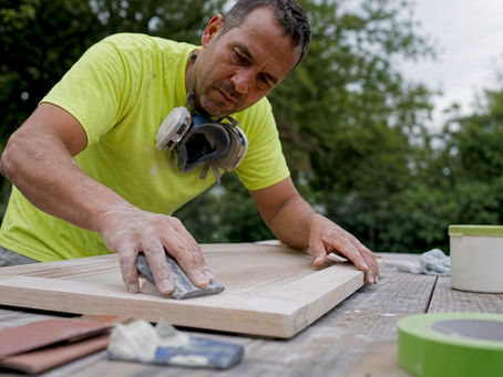 Cabinet painter sanding doors in workshop