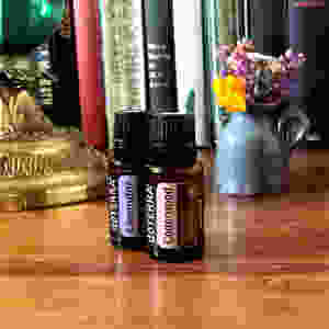 2 bottles of Lavender and Cedarwood essential oils near books and flowers in a study