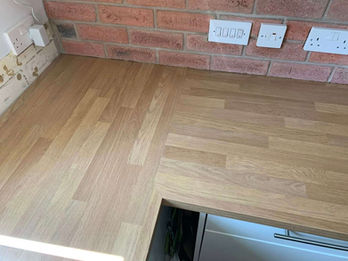 Close-up of a light wooden countertop or floor surface set against exposed brickwork