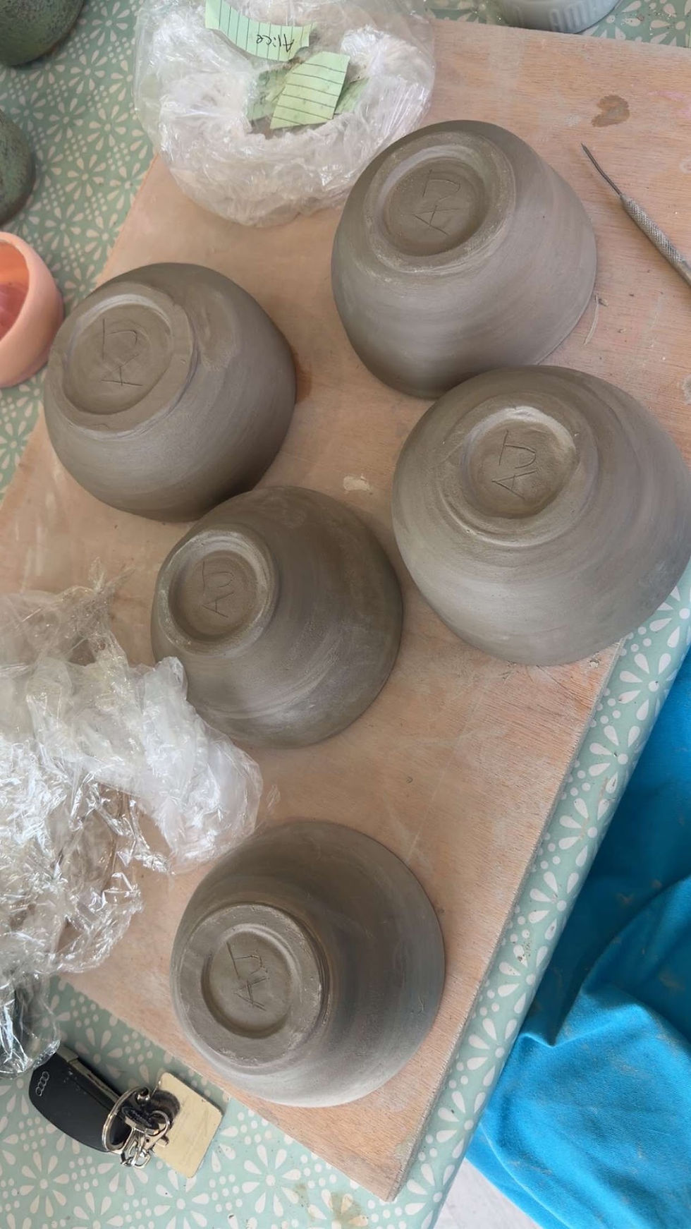 Hand-thrown clay bowls turned upside down on a workbench showing trimmed foot rings drying in a ceramic studio
