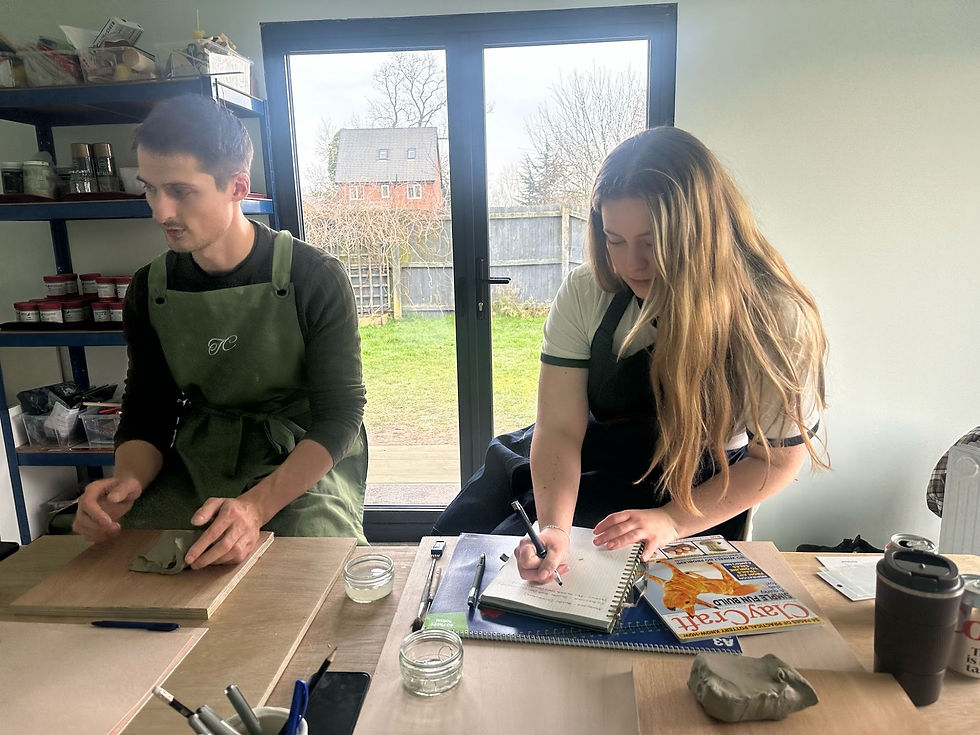 Students sketching design ideas and working with clay in aprons during a pottery class