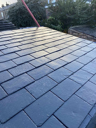Close-up angle of newly laid dark grey slate or composite roof tiles on a residential house