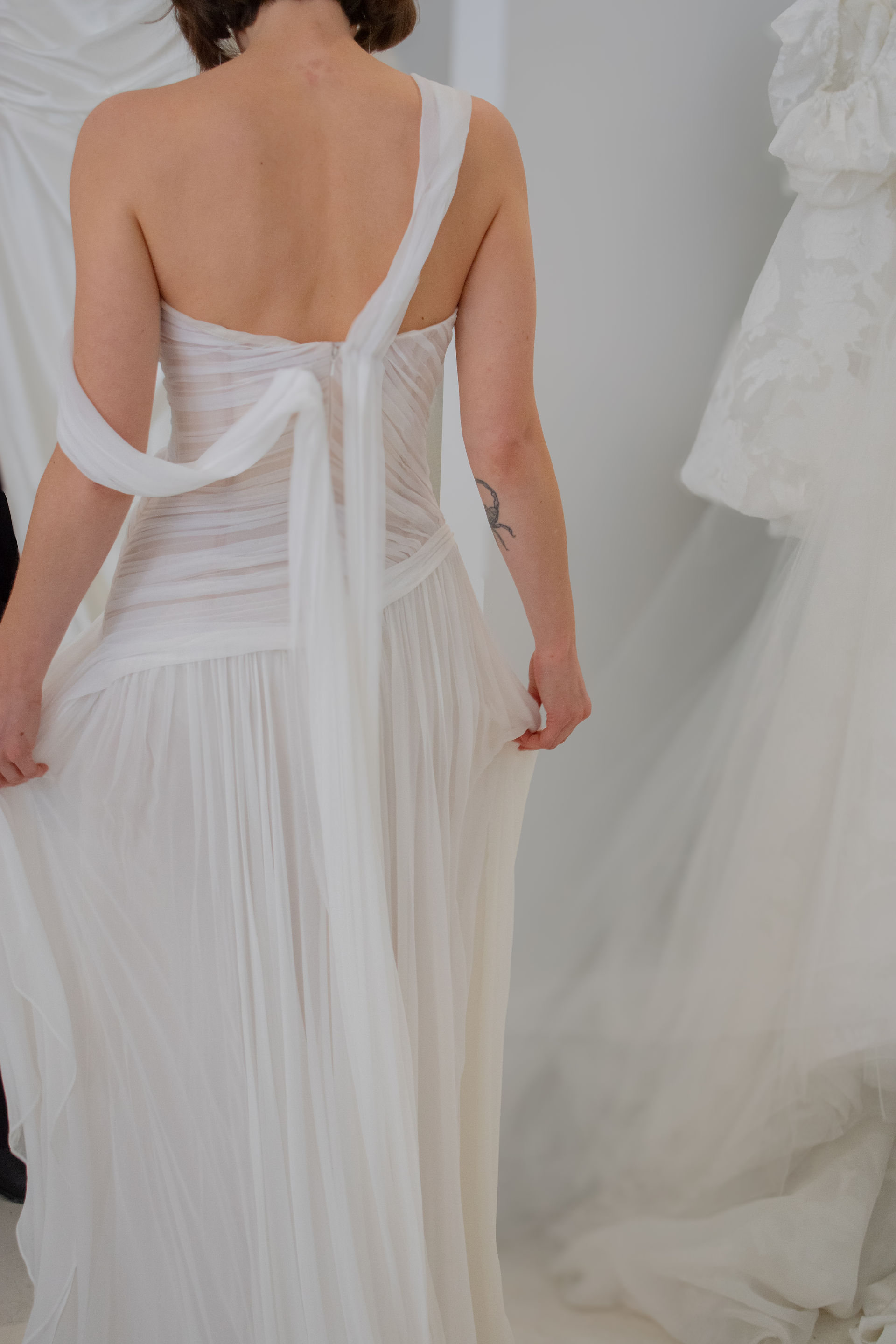 back of a brides wedding gown OUMA premiered her Spring 2026 Collection, "Echo," in NYC at One Fine Day Bridal Market, showcasing her sustainable practice of upcycling scrap fabric into dainty details, veils, bags, and earrings. 