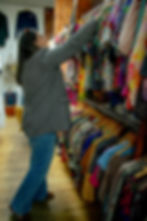 Woman in a thrift store in NYC looking through the clothing rack of women vintage tops