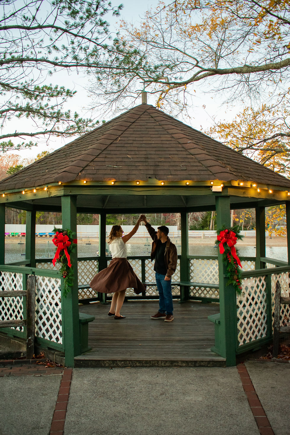 Engaged couple twirling in gazebo after engagement photos
