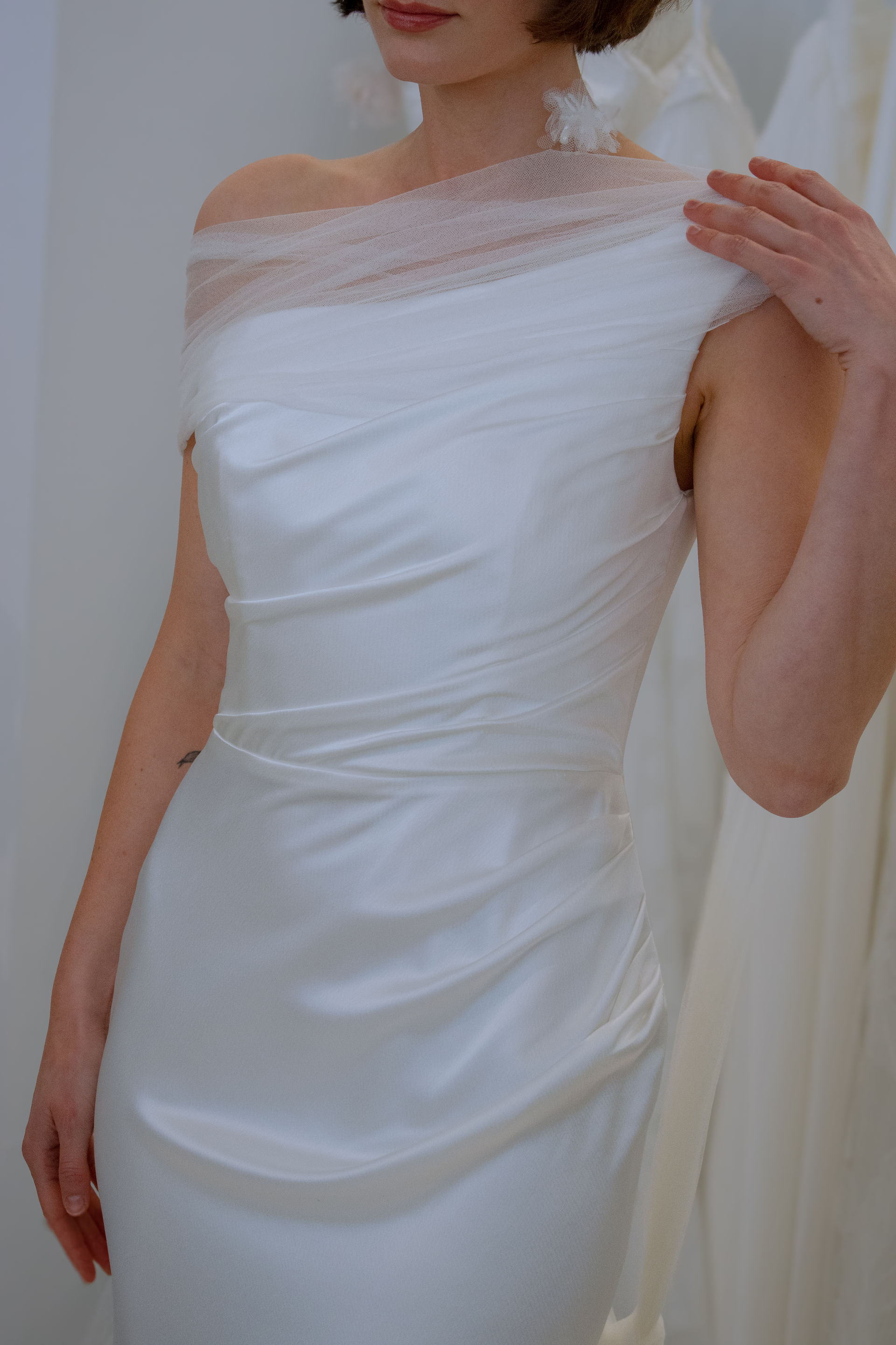 Close up of a bride in a silk wedding dress. OUMA premiered her Spring 2026 Collection, "Echo," in NYC at One Fine Day Bridal Market, showcasing her sustainable practice of upcycling scrap fabric into dainty details, veils, bags, and earrings. 