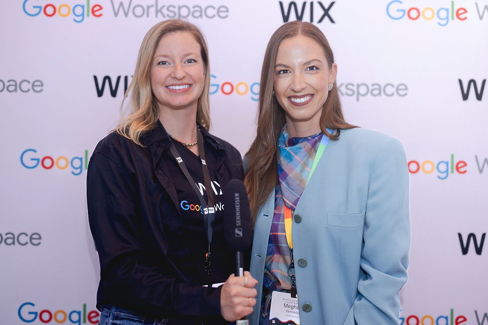 Two women smile at a Google Workspace and WIX event. One holds a microphone. Background has event logos. Bright, professional setting.
