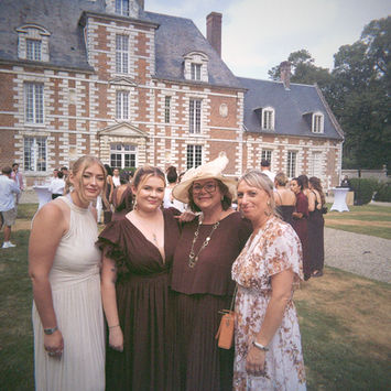 Quatre femmes posant devant un château lors d'un mariage.