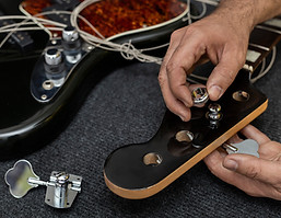 luthier-s-hands-placing-adjusting-peg-electric-bass.jpg