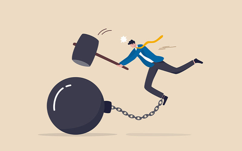 Man trying to break a chain and ball with a hammer