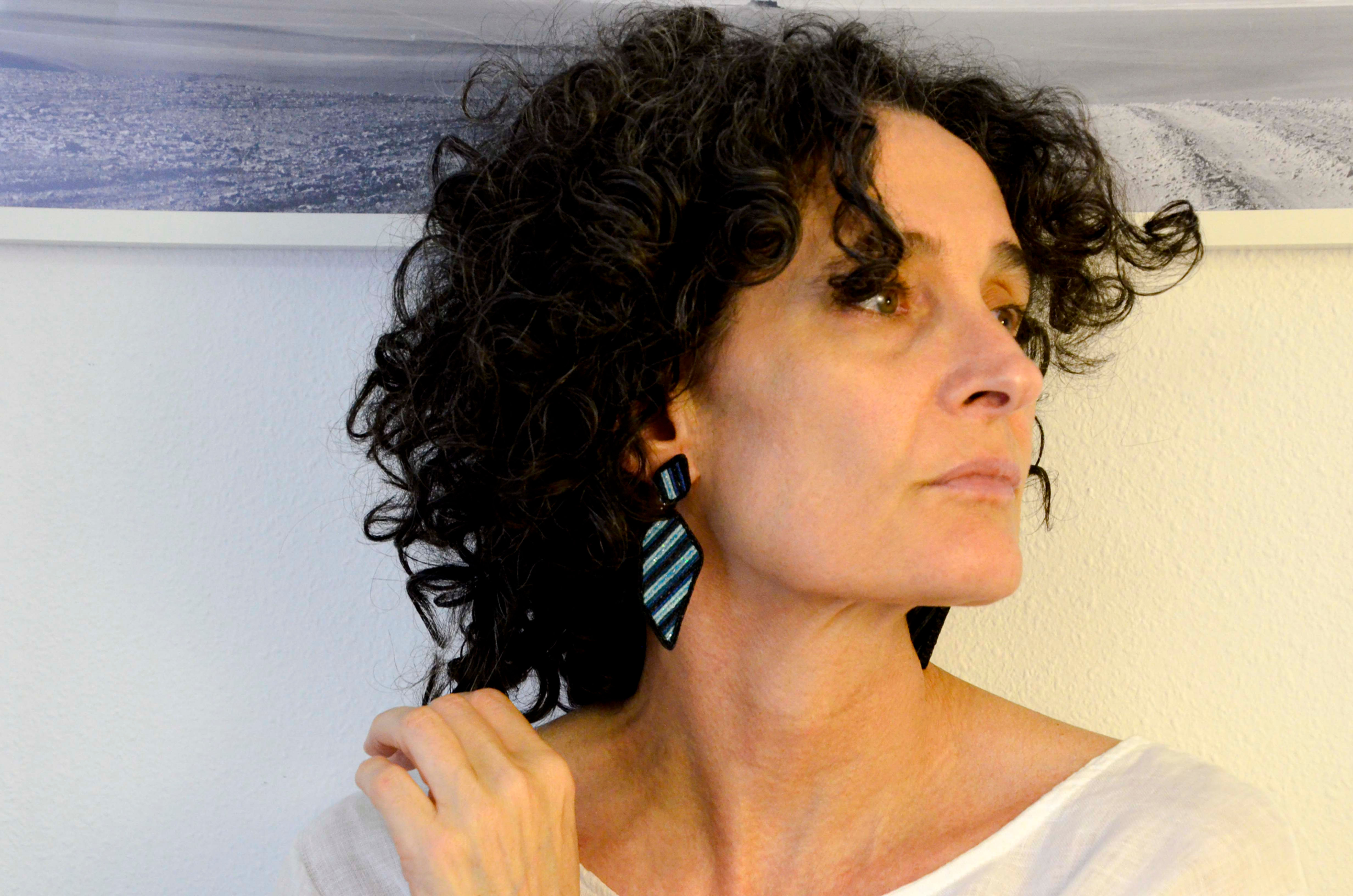 Mujer luciendo pendientes modelo Argentina, joyería textil de diseño realizados en diferentes combinaciones de color.