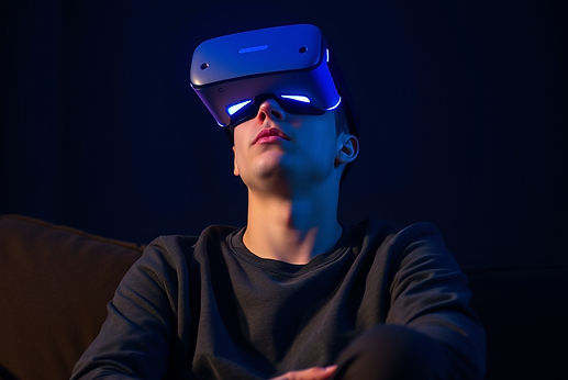 an early 20's male sitting on a couch in a darkened room with a VR headset on with a look