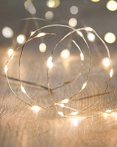 String lights on a wooden surface glow warmly. Blurred lights in the background create a cozy and festive atmosphere.