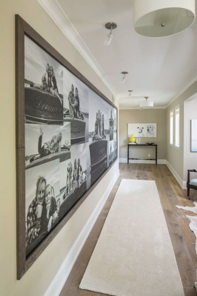 Hallway with a large black-and-white photo collage on the left wall, a light carpet runner on wooden floor, and bright, airy decor.