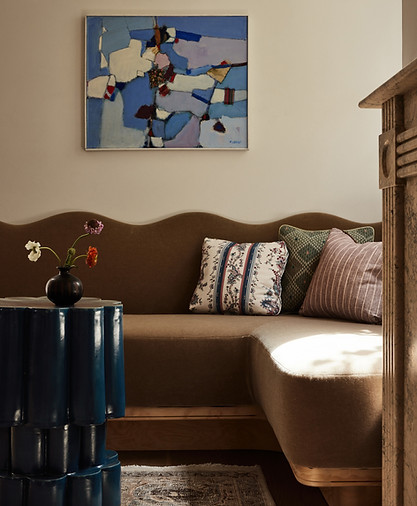 Living room with corner mohair sofa with waived top and new england inspired pillows. Modernis art and studio pottery table contrast the custom marble mantle. 